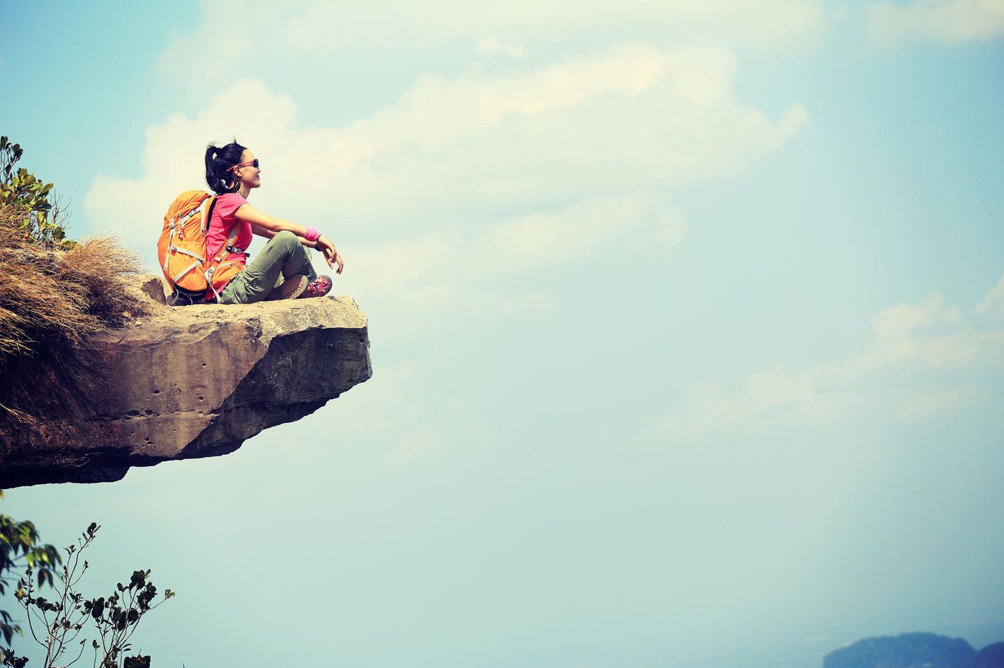 Ängste überwinden: Eine Frau sitzt auf einer Klippe