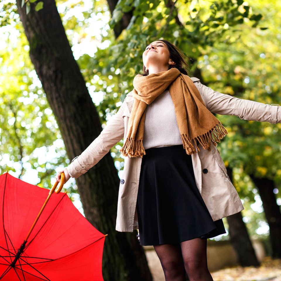 Leben genießen: Eine Frau mit Regenschirm in der Hand genießt die Luft