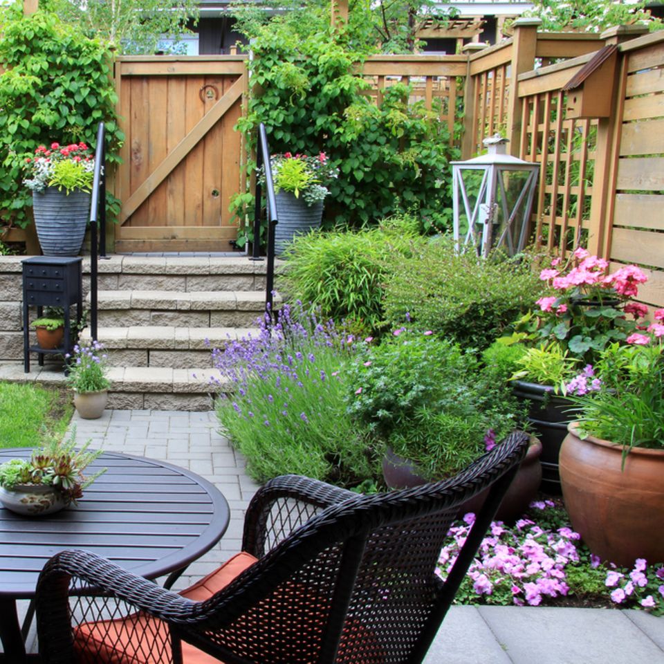 Kleiner Garten: So gestaltest du ihn richtig! Garten mit Stühlen, Tisch und Blumen links und rechts