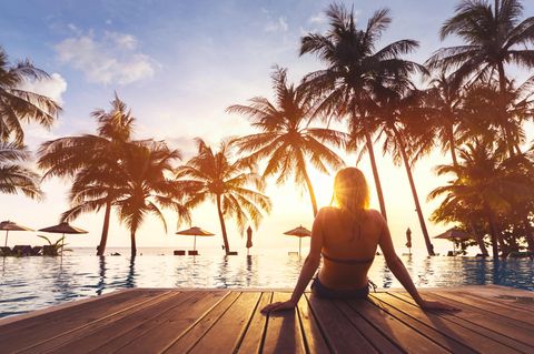 Unbezahlter Urlaub: Frau entspannt am Pool unter Palmen