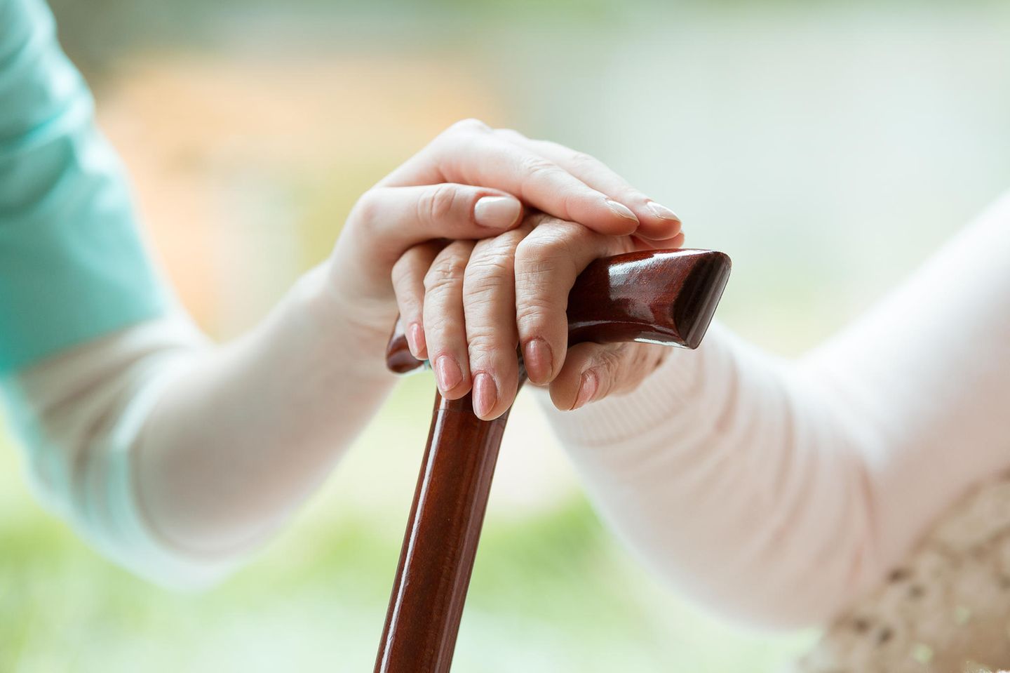Mehr Geld für soziale Berufe: Pflegerin hält die Hand einer alten Frau