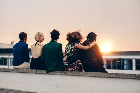Gemeinsamer Freundeskreis: 5 Menschen beobachten Sonnenuntergang