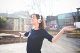 Kraftquellen der Redaktion: Eine Frau tanzt mit Kopfhörern auf den Ohren