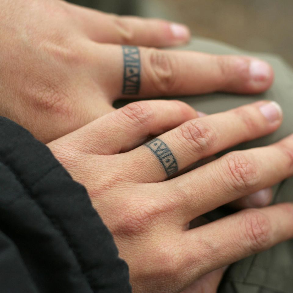 Partner Tattoo: Ein Paar mit tätowierten Ringen auf den Fingern