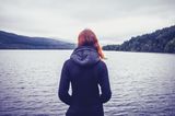 Gewohnheiten erfolgreicher Frauen: Eine Frau schaut auf einen See