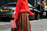 Outfits, die wir zur Arbeit anziehen: Frau mit Midirock und rotem Pullover