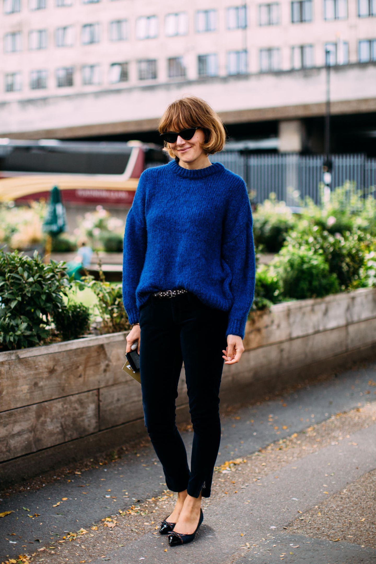 Outfits, die wir zur Arbeit anziehen: Frau mit blauem Pullover und schwarzer Hose