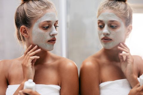 Hautprobleme durch Stress: Frau schaut sich ihr Gesicht im Spiegel an