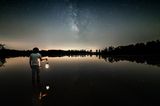 Eheversprechen: praktische Tipps und Beispiele: Mann hält Laterne in der Hand in der Dämmerung und steht vor einem großen See
