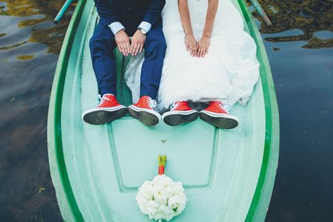 5 besondere Hochzeitslocations: Brautpaar sitzt auf dem Bug eines Bootes, der Blumenstrauß liegt vor den beiden