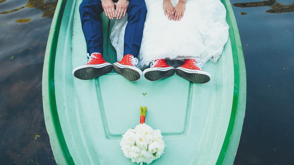 5 besondere Hochzeitslocations: Brautpaar sitzt auf dem Bug eines Bootes, der Blumenstrauß liegt vor den beiden