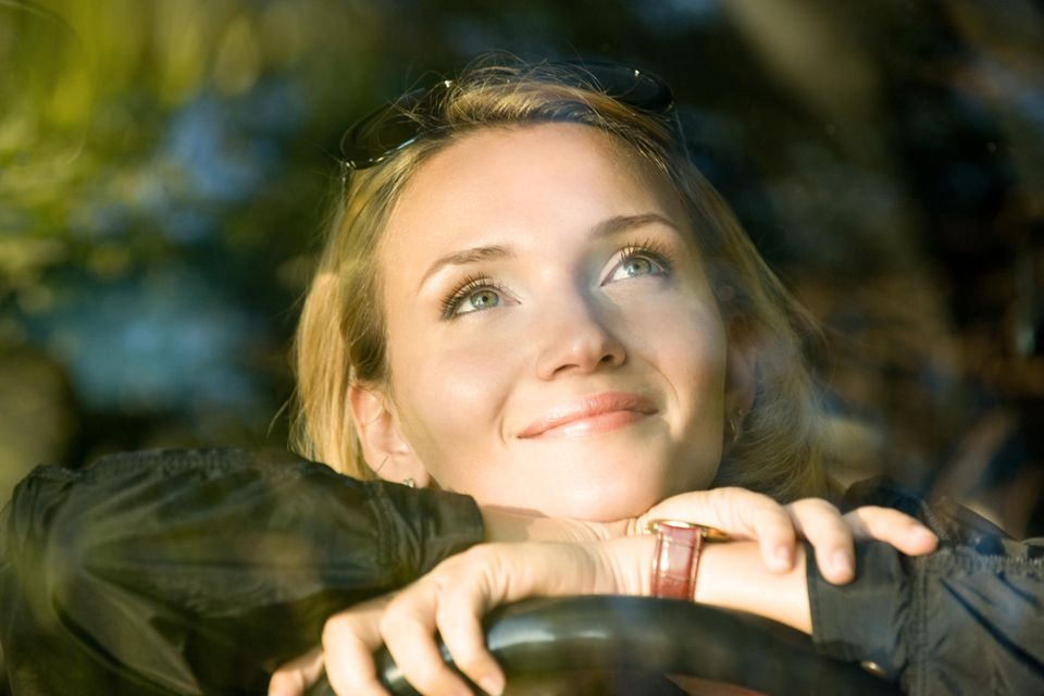 Gedanken-Trick für gute Laune: Eine fröhliche Frau schaut nachdenklich nach oben