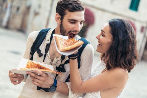 Was sollte man nicht mit dem Partner teilen? Eine Frau lässt ihren Freund von ihrer Pizza abbeißen