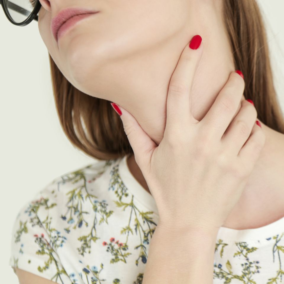 Schilddrüse: Frau fasst sich an den Hals