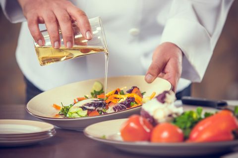 Ernährung bei Arthrose: Koch kippt Öl über Salat