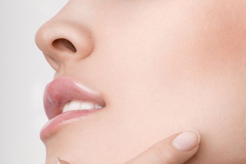 Nasenhaare entfernen: Frauengesicht bei dem Nasen- und Mundbereich sowie eine Hand zu sehen ist