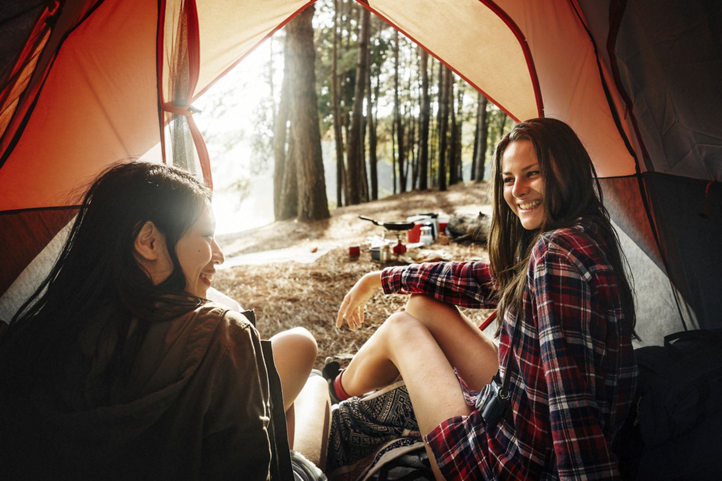 Camping Tipps für einen gelungenen Urlaub: Zwei Frauen sitzen im offenen Zelt und lachen