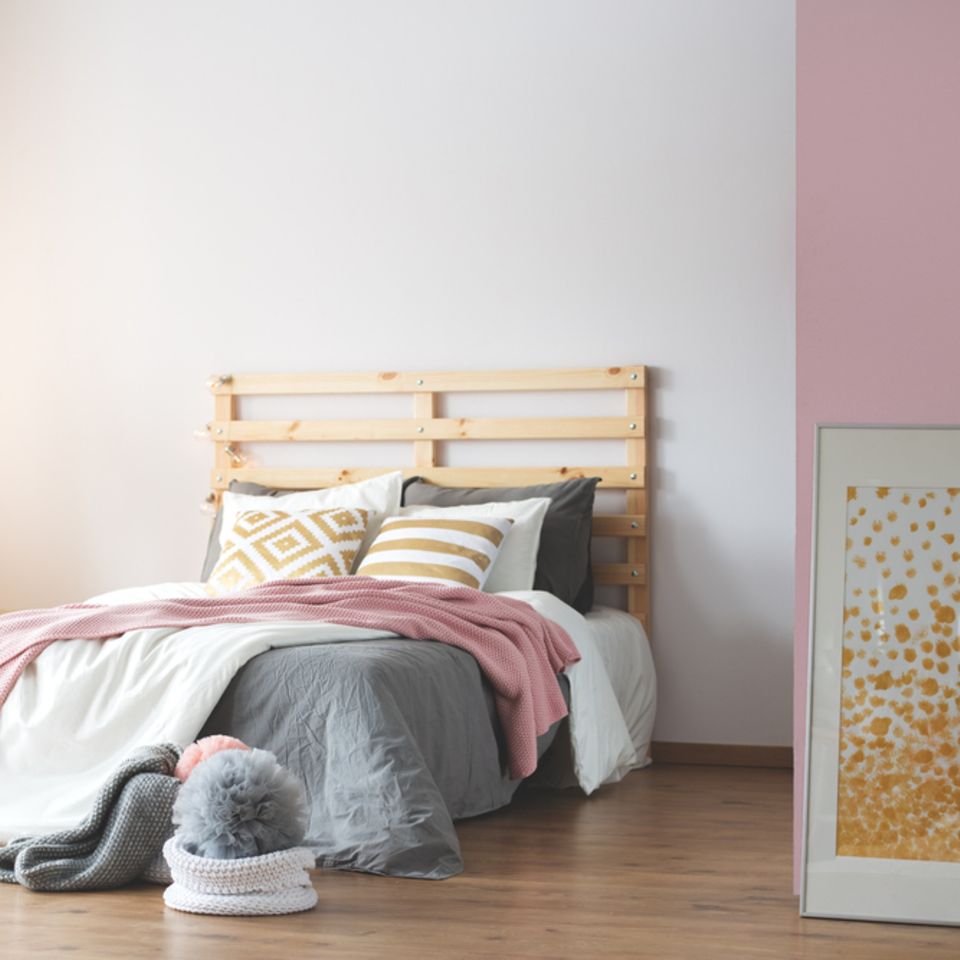 Wandgestaltung Schlafzimmer: 6 kreative Ideen: Bett mit rosa Decke und rechts einer rosafarbenen Wand