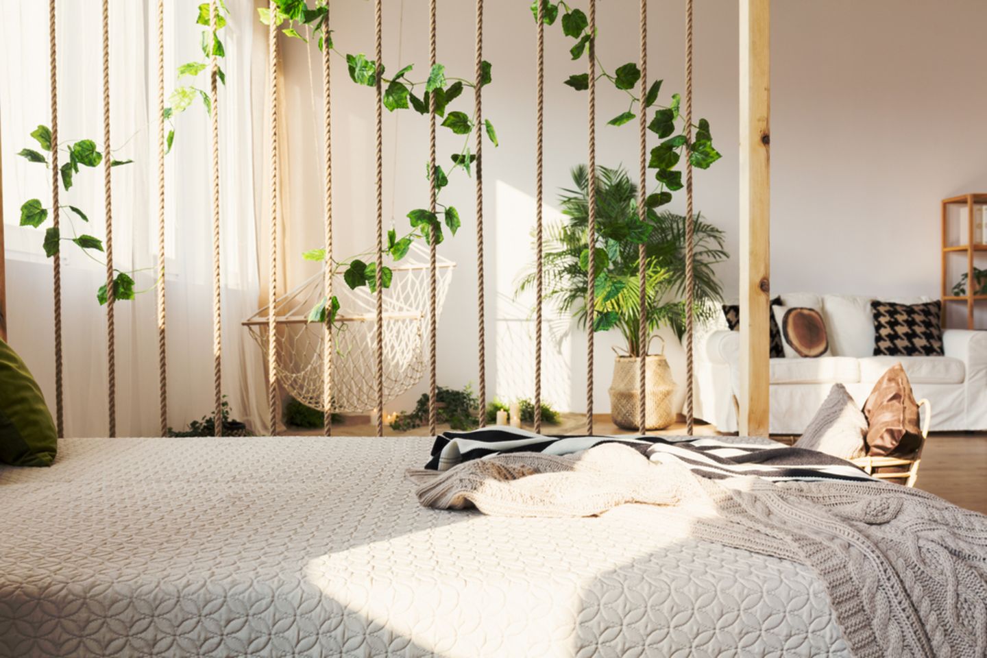 Raumteiler Ideen: 9 kreative Lösungen: Bett mit einem Raumteiler aus Seilen und Pflanzen, dahinter Sofa und Hängematte