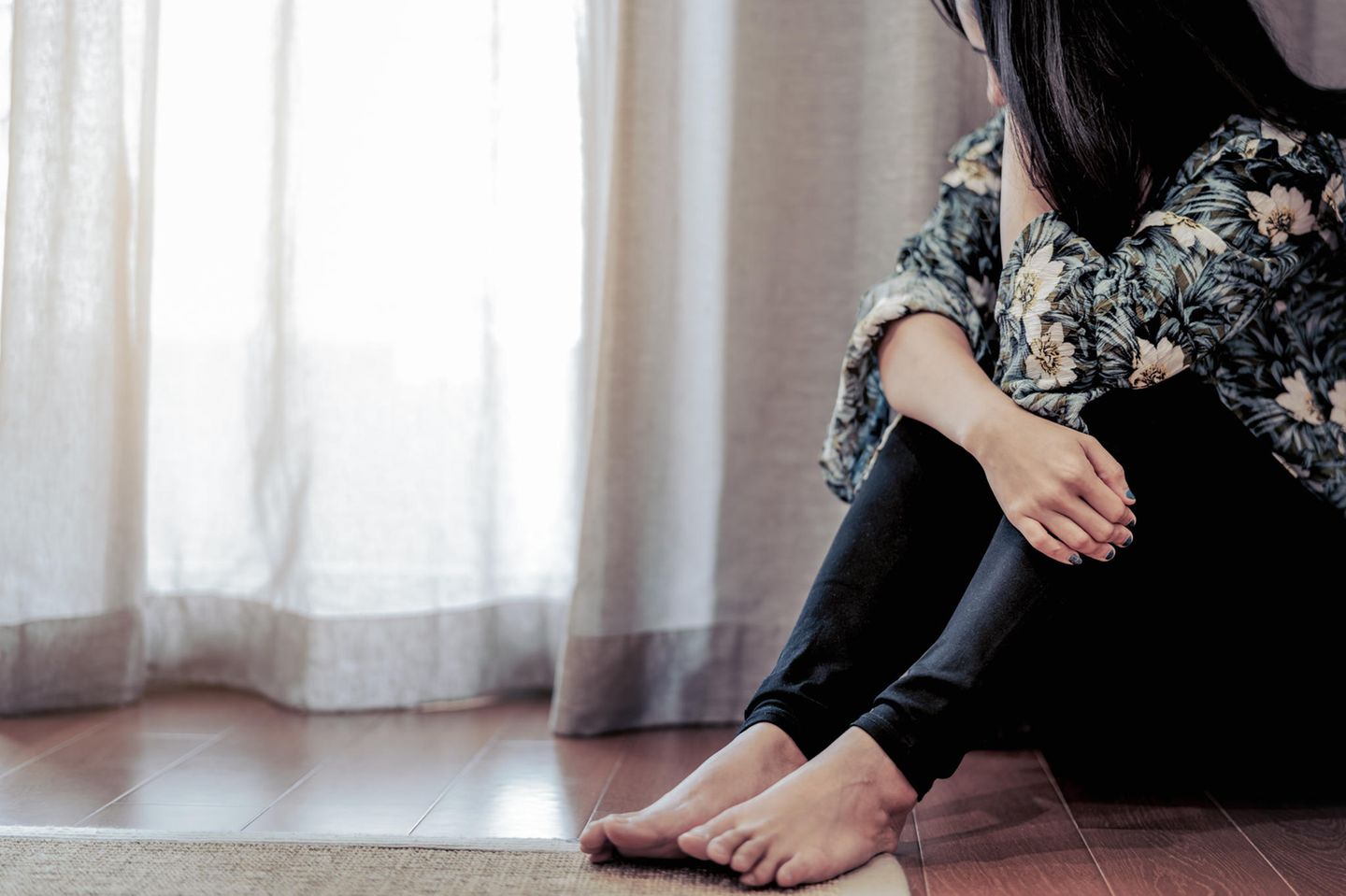 Psychisch krank: Frau sitzt deprimiert auf dem Boden