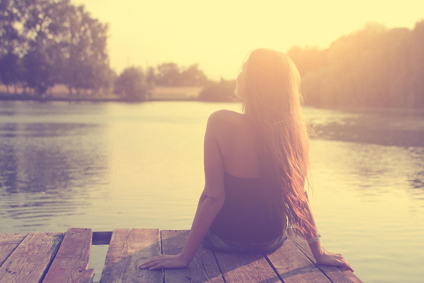 Sonnenstich-Anzeichen: Frau sitzt am Bootssteg in der Sonne