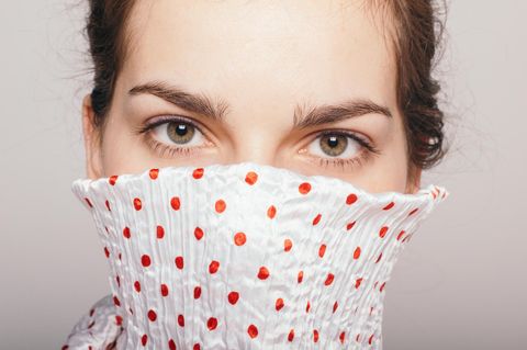 Welche Probleme hat man als introvertierter Mensch? Eine Frau versteckt ihr Gesicht mit dem Kragen ihrer Bluse