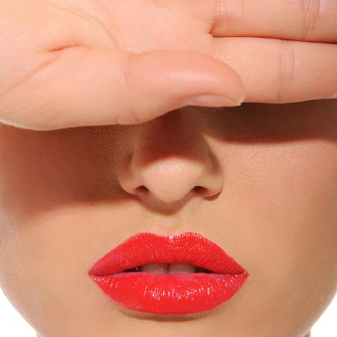 Augenringe abdecken: Frau mit roten Lippen hält sich die Hand vor die Augen