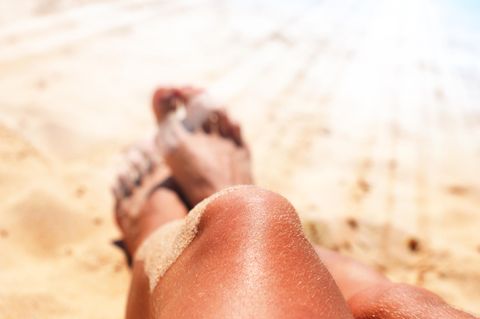 Hitzschlag-Symptome: Stark gebräunte Beine im Sand