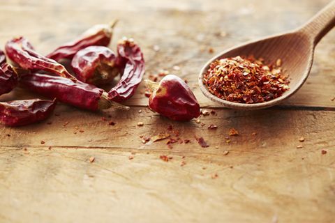 Peperoni trocknen: Methoden und praktische Tipps: Getrocknete Peperonischoten neben einem Holzlöffel mit Peperoni-Flocken