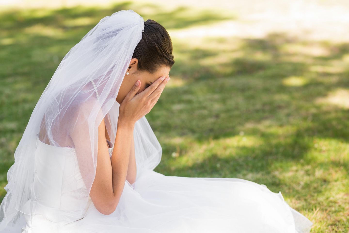 Erfahrungsbericht: Weinende Braut kniet auf einer Wiese