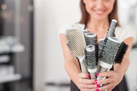 Haarbürste reinigen in drei Schritten: Frau hält viele Haarbürsten in der Hand