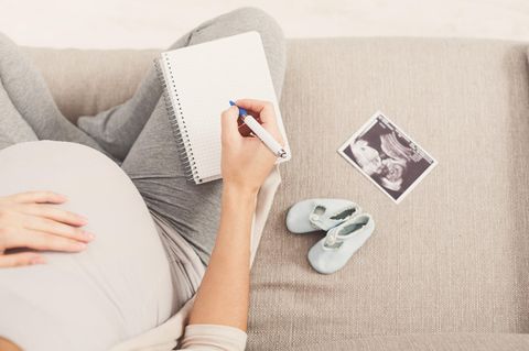 Babynamen: Schwangere Frau mit Ultraschall und Notizblock