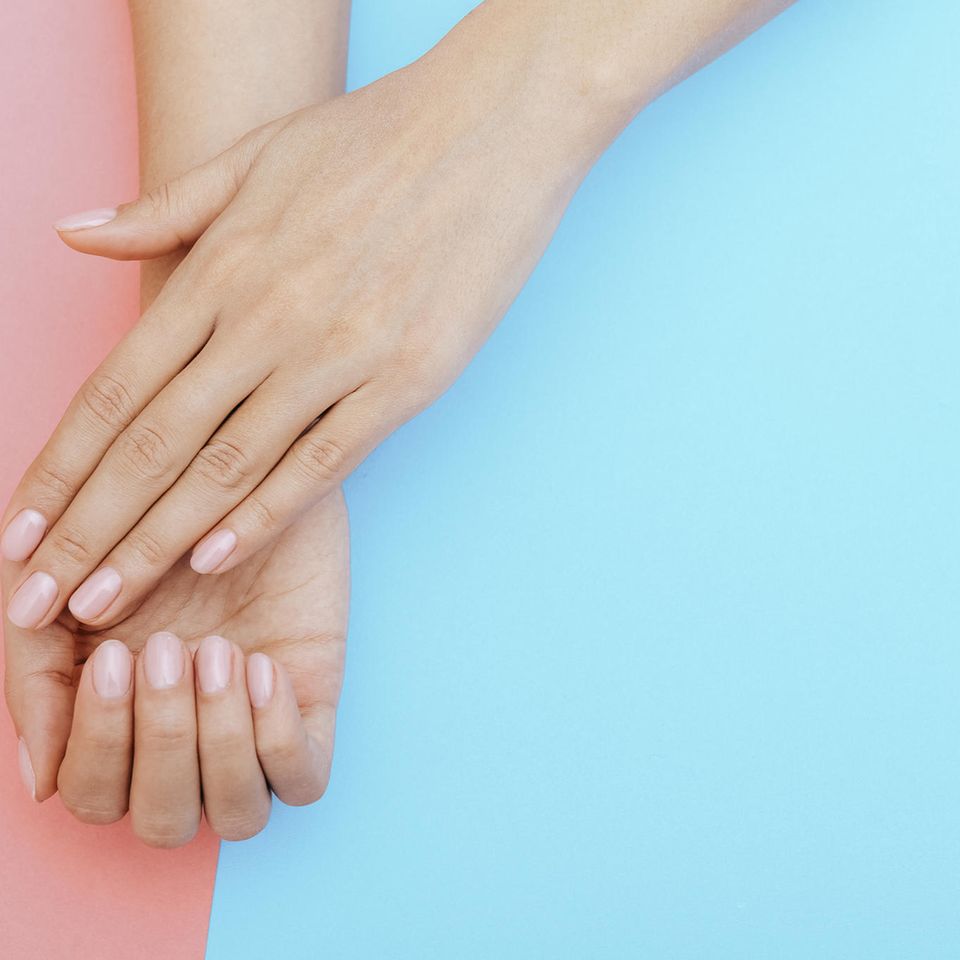 Eingerissene Nagelhaut: Zwei Hände mit rosafarbenen Fingernägeln