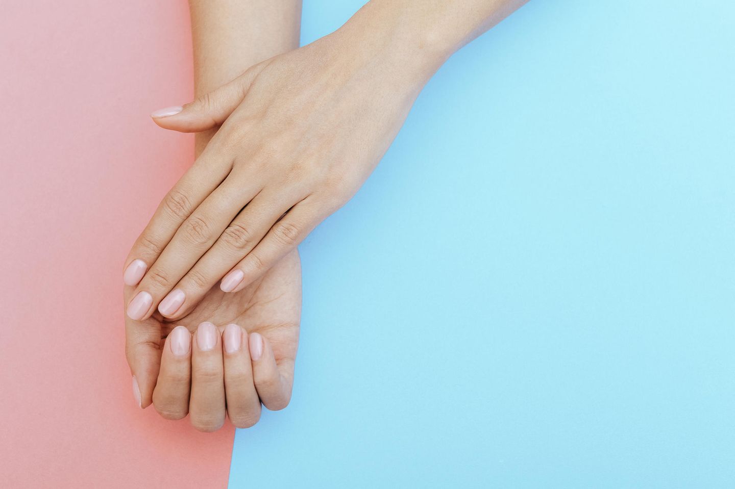 Eingerissene Nagelhaut: Zwei Hände mit rosafarbenen Fingernägeln