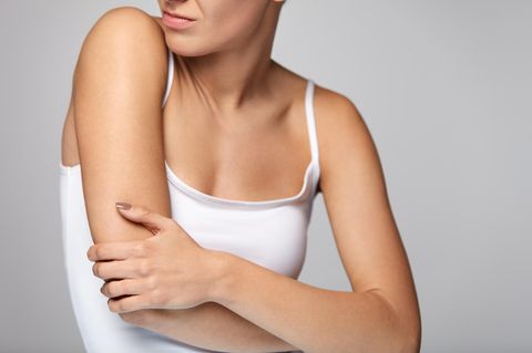 Thrombose im Arm: Frau hält ihren Arm fest