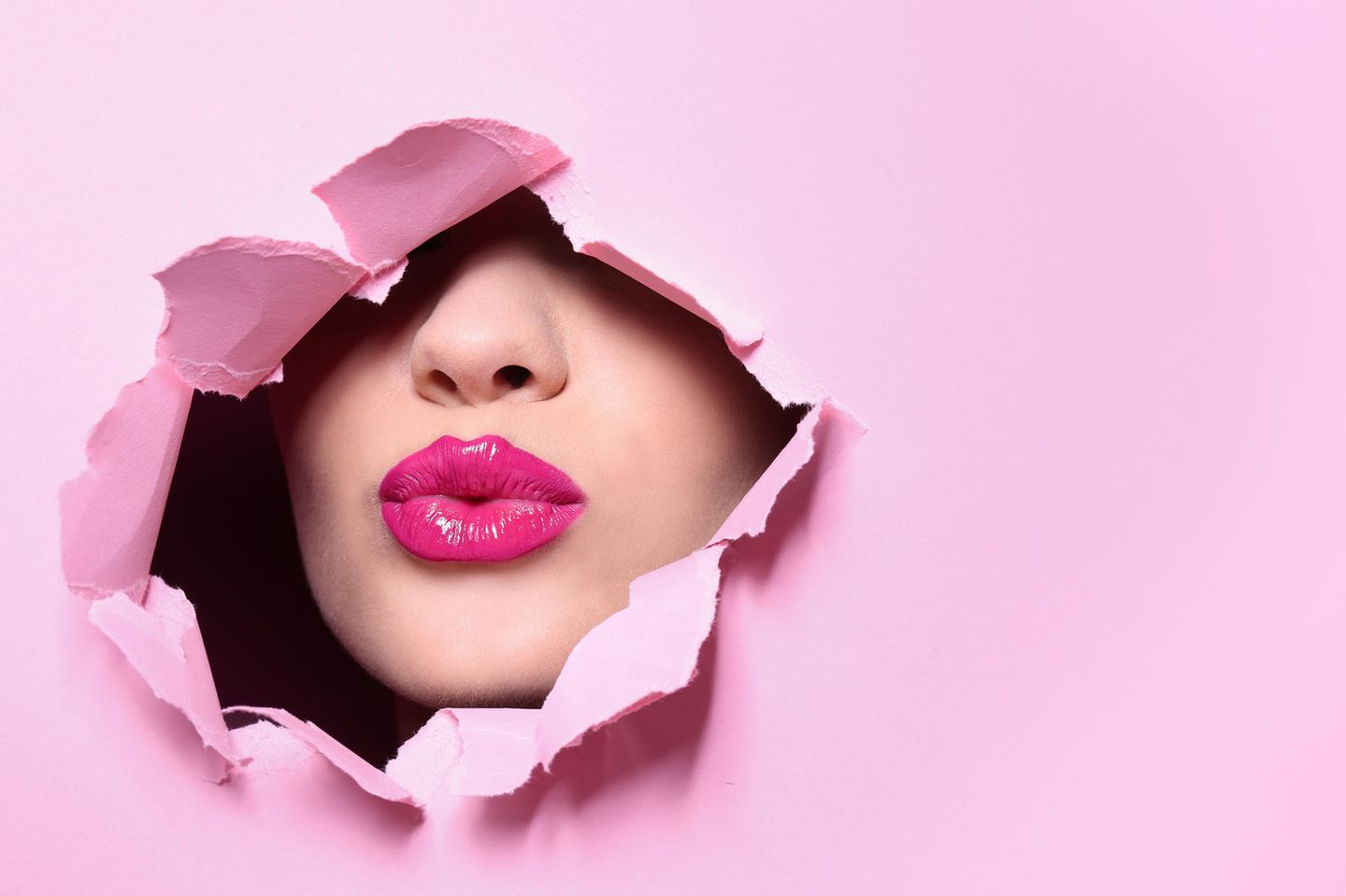 pinker Lippenstift: Gesicht mit pinkem Lippenstift durch eine Paierwand
