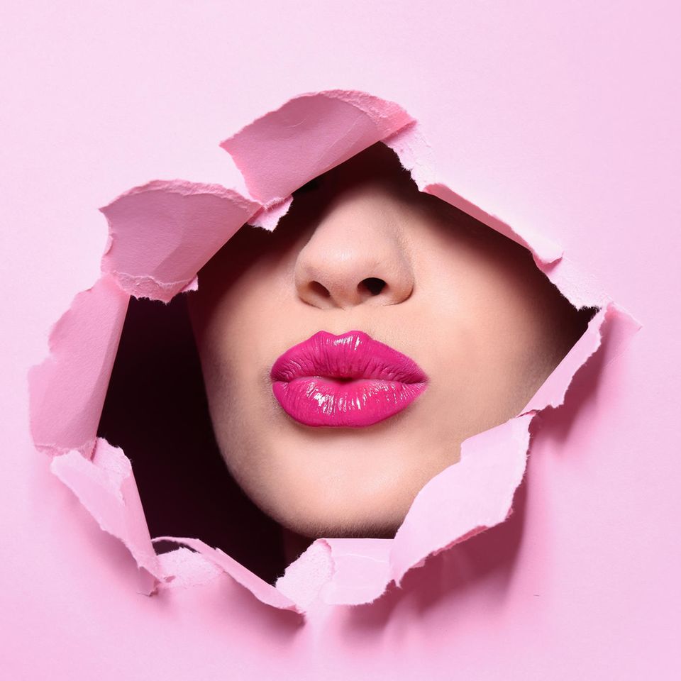 pinker Lippenstift: Gesicht mit pinkem Lippenstift durch eine Paierwand