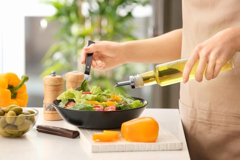 Fette Irrtümer: Frau gießt Olivenöl in Salat