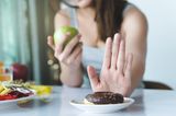 Vermeide Zucker: Frau isst Apfel statt Donat