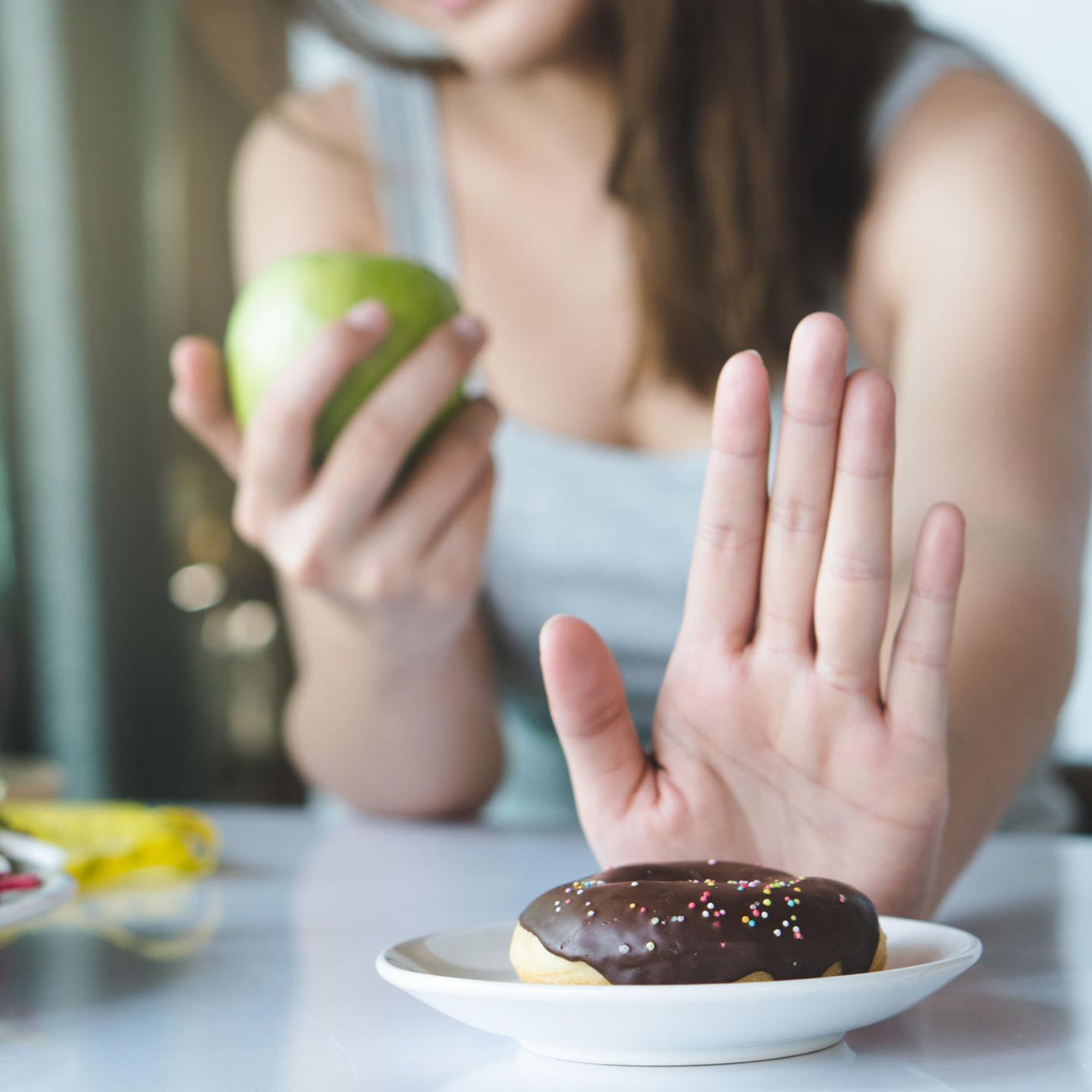 Vermeide Zucker: Frau isst Apfel statt Donat