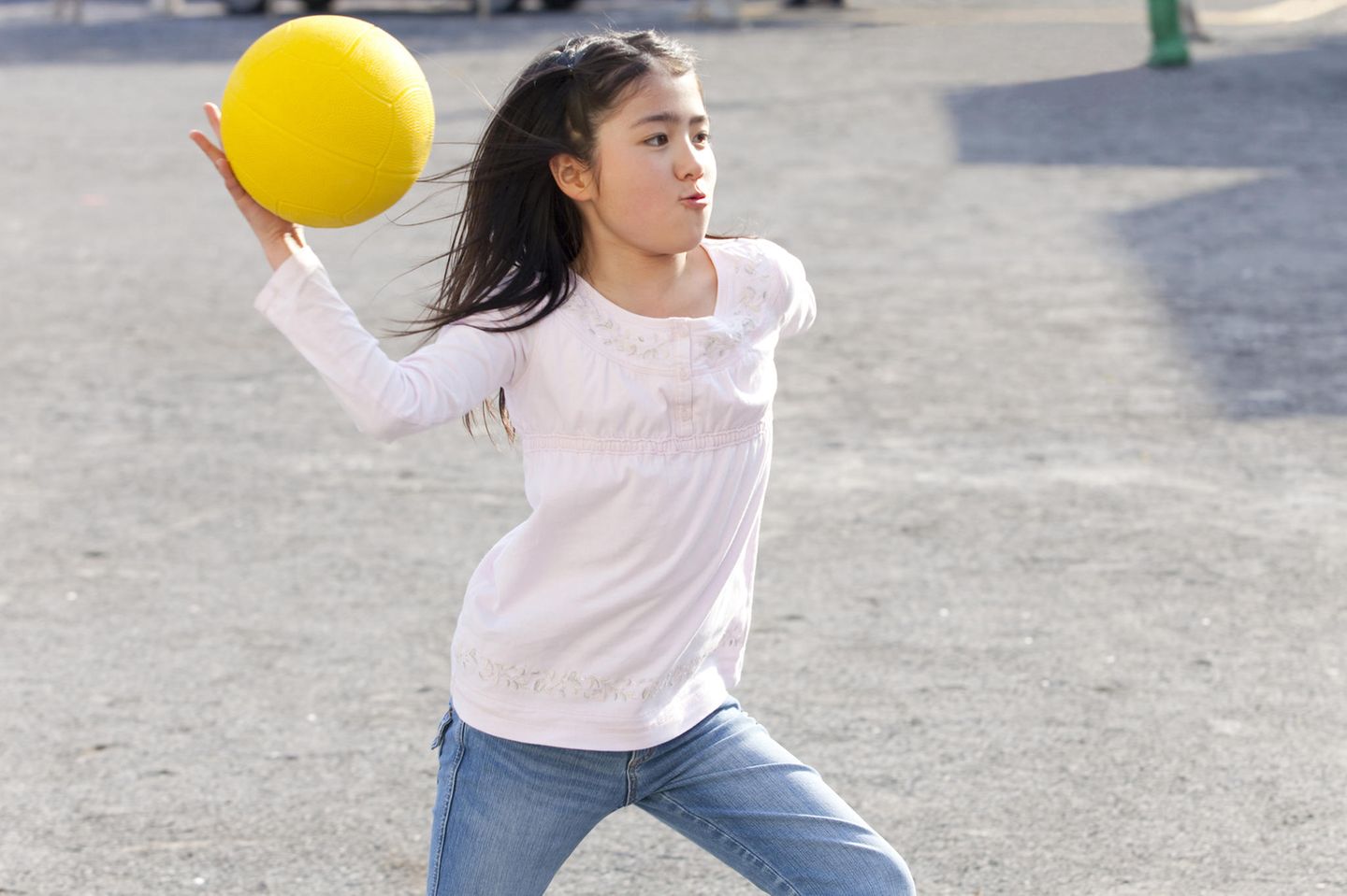 Völkerball: Dunkelhaariges Mädchen wirft gelben Ball