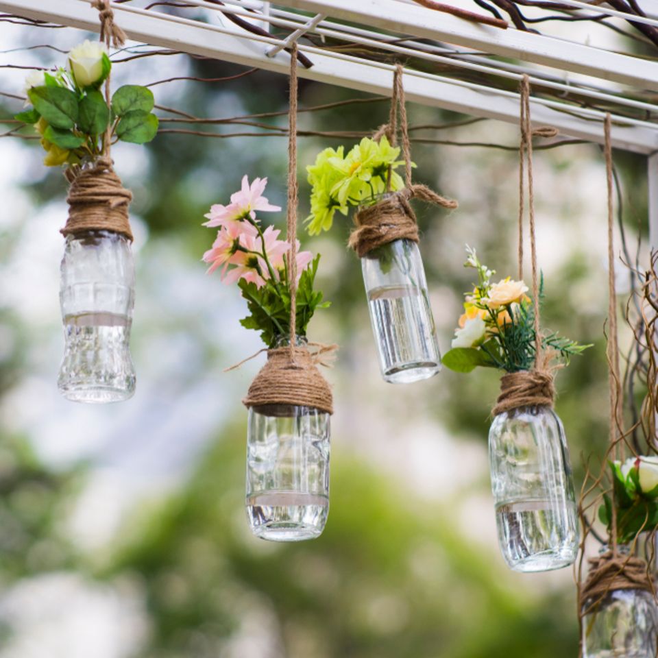 Gartendeko selber machen: Flaschen mit Blumen hängen von Gartentor