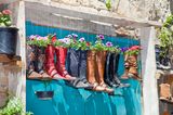 Gartendeko selber machen: Stiefel hängen über eine Tür und sind mit Pflanzen gefüllt