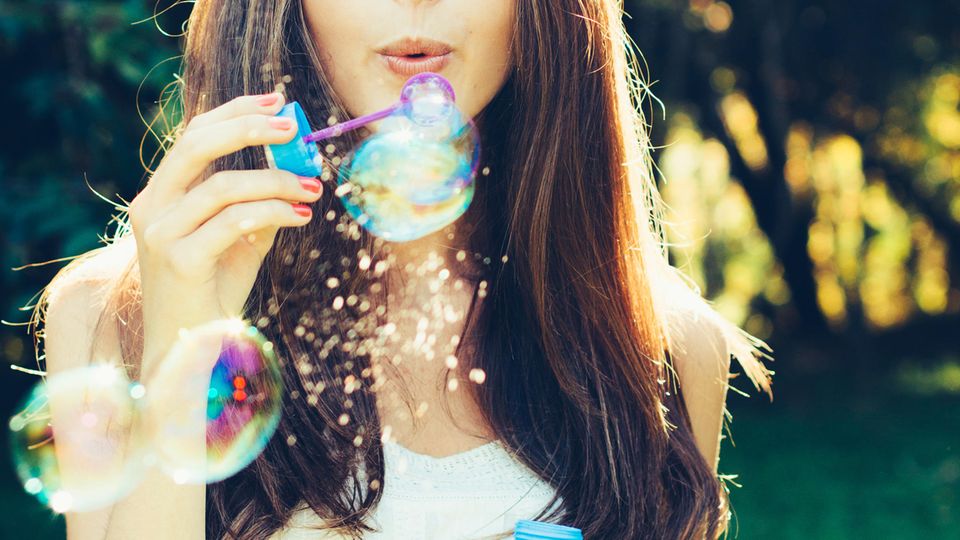 Seifenblasen selber machen: Frau pustet Seifenblasen