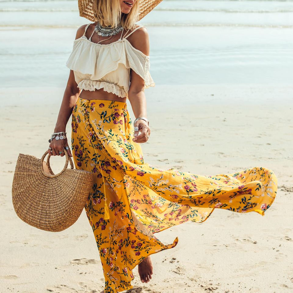 Frau am Strand mit Sommerrock und Sonnenhut und geflochtener Korbtasche