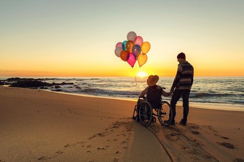 Frau im Rollstuhl mit ihrem Partner am Strand