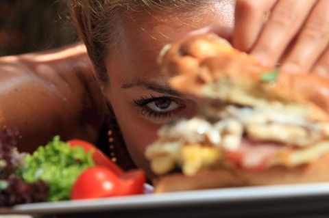 Kein Sättigungsgefühl: Frau schaut sich Burger an