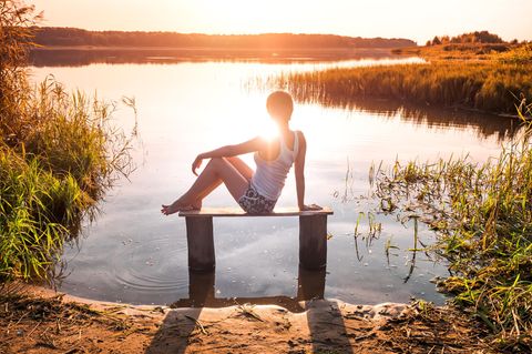 Horoskop: Eine einsame Frau sitzt vor einem See