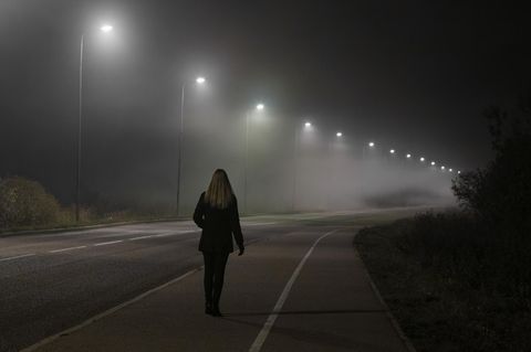 Sicherer Nachhauseweg: Frau läuft eine dunkle Straße entlang
