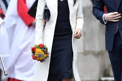 Ohne Babybauch, dafür wie immer super stylisch: Der weiße Mantel ist der perfekte Kontrast zu Meghans schwarzem Midikleid.